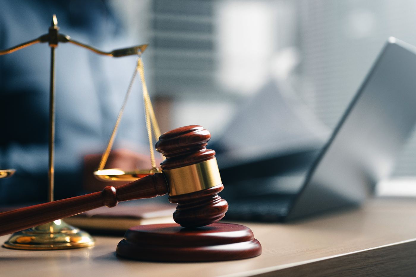 A gavel and scales of justice on a desk beside a laptop