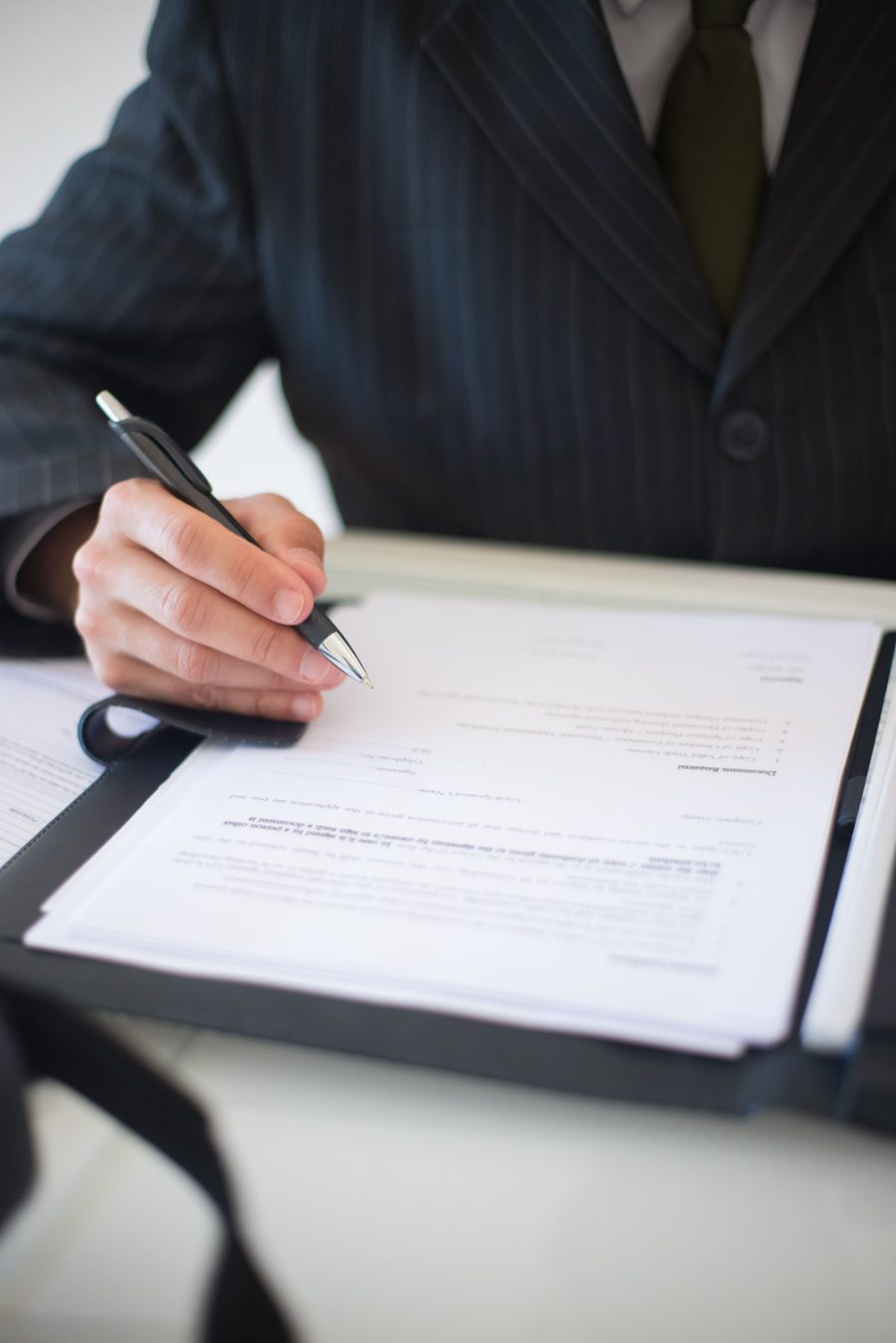 Hands, a pen, and paperwork on a desk