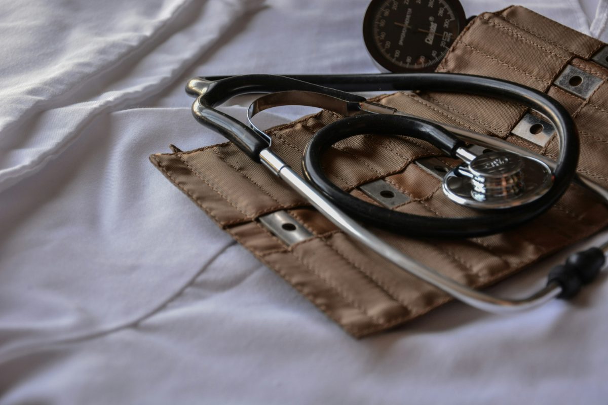 A stethoscope and blood-pressure cuff resting on a hospital bed